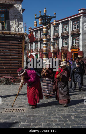 Older Tibetan women in traditional dress circumambulate the Jokhang Temple kora or circuit with their pray wheels in Lhasa, Tibet. Stock Photo
