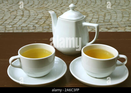 Two cups of hot tea with teapot on terrace's wooden table Stock Photo