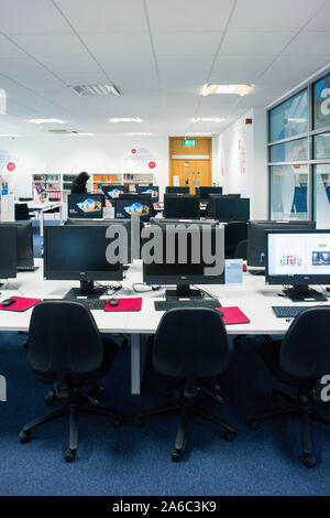 A college or University library with books on the shelves, students and computers Stock Photo