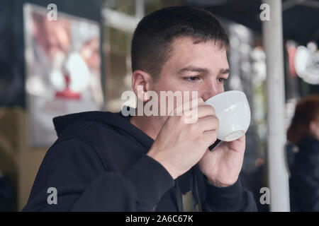 young man drinking a coffee in a cafe terrace Stock Photo