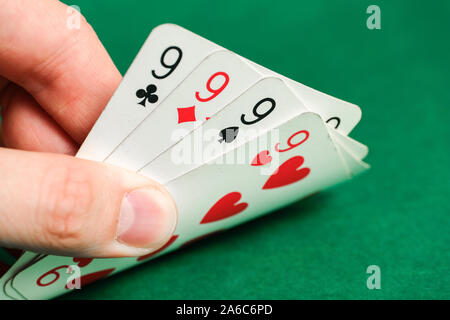 Hand holds a combination in poker - four of a kind on a green background. Close up. Stock Photo
