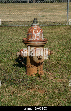 An old rusty fire hydrant in grass at a park still in use on a bright sunny day Stock Photo