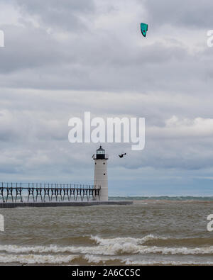 A kite surfer flies high in front of the Manistee North Pierhead Lighthouse in Michigan, USA. Stock Photo
