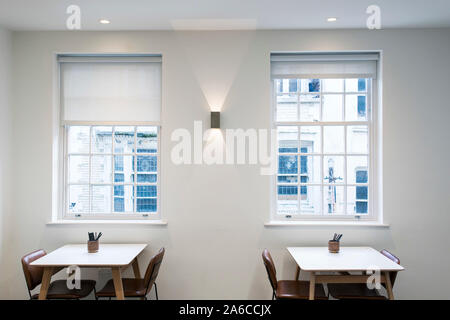 A plane clean white room in a restaurant / coffee shop with two tables and chairs Stock Photo