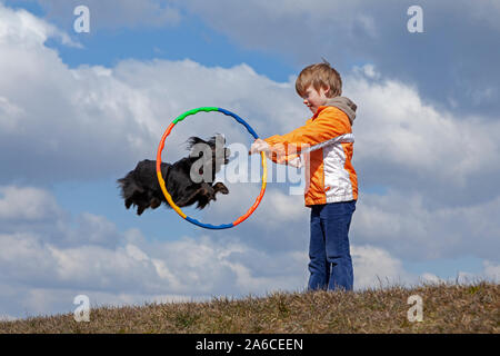 A young boy is making his dog jump through a hoop. Stock Photo