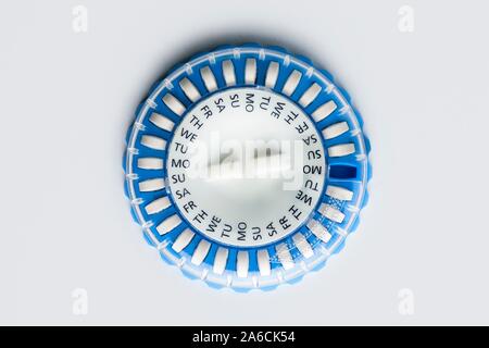 Circular pill dispenser containing hormone replacement therapy (HRT) pills. The days of the week printed on it help to remind the patient when to take the medication. HRT utilises synthetic female hormones to relieve the symptoms of either the menopause or surgical removal of the ovaries. It can also slow the loss of bone density (osteoporosis). Stock Photo