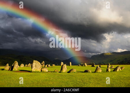 Rainbow over Castlerigg Stone Circle on summer solstice eve with sun and dark clouds over Cumbrian Mountains in Lake District Keswick England Stock Photo
