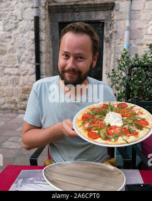 smiling bearded man posing with pizza in his hands Stock Photo