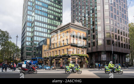 The Albert public house with police on motorbikes passing by on the road in Westminster, London, UK