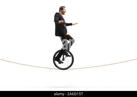 Full length shot of an excited young businessman riding a unicycle on a rope isolated on white background Stock Photo