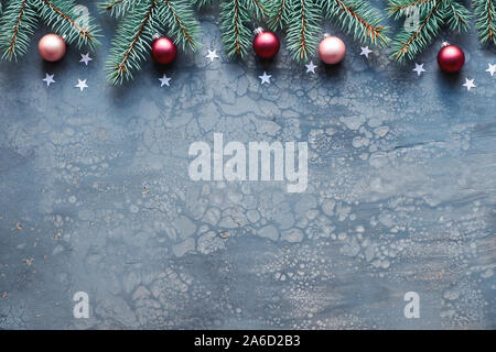 Christmas background with fir twigs, pink and dark red baubles and silver stars on dark abstract grey fluid art acrylic background with plenty of text Stock Photo
