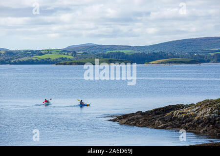 A pair of kayakers paddling around the coastline of the Bantry Bay in West Cork, Ireland. Stock Photo