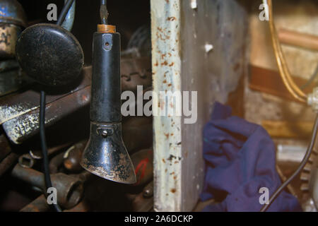 Old wired rusty flashlight near the rack with tools in the garage closeup with lens flare Stock Photo