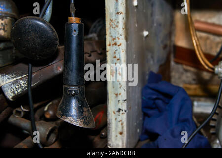 Old wired rusty flashlight near the rack with tools in the garage closeup Stock Photo