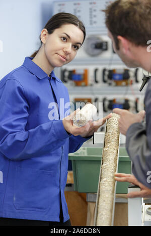 portrait of engineer and apprentice examining component in factory Stock Photo