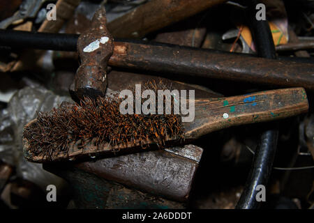 Rusty Metal brush and hammer on the gripe with rusty wrenches made in USSR and other instruments on the background Stock Photo