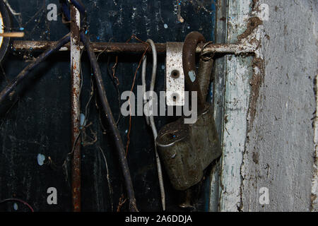 Old rusty padlock on the wall closeup in the old workshop in the Russia Stock Photo