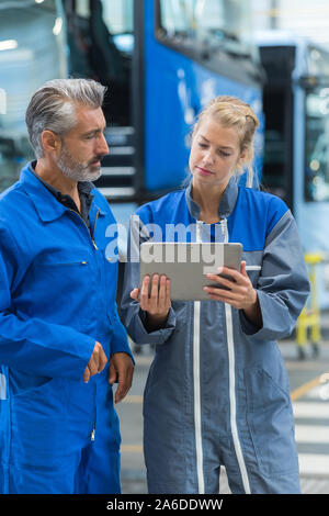 female mechanic looking at tablet with senior male colleague Stock Photo