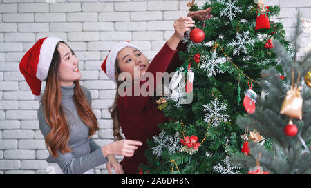 Asian woman decorating Christmas tree, preparing for Christmas holiday in December Stock Photo