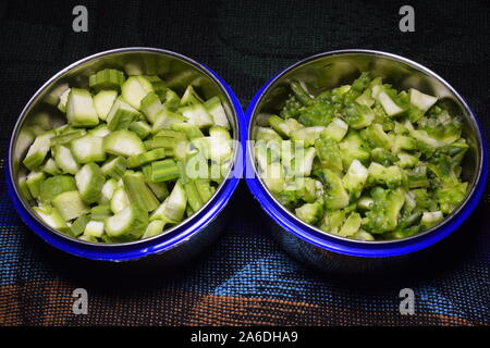 Fresh bitter gourd and okra fruits pieces in two bowls, Stock Photo