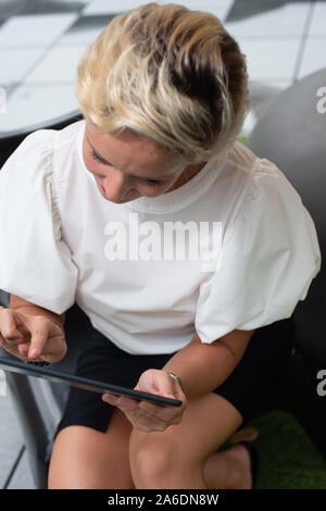 Portrait of one confident short hair Caucasian business woman using mobile device tablet. Empty copy space for text. Stock Photo
