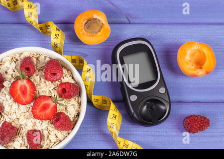 Glucometer for measuring sugar level, oat flakes with fruits and tape measure. Concept of diabetes, diet, slimming and healthy lifestyles Stock Photo