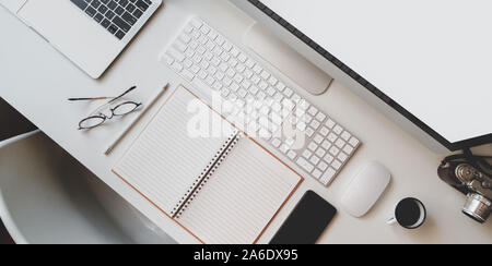 Cropped shot of modern workplace with open blank notebook, keyboard computer and desktop computer with office supplies Stock Photo