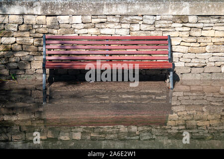 park bench with its feet in water and reflection against a stone wall ,effects of global warming & water levels rising.  Vaucluse.France Stock Photo