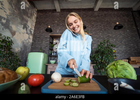 Beautiful girl talking on the mobile phone in kitchen at home Stock Photo