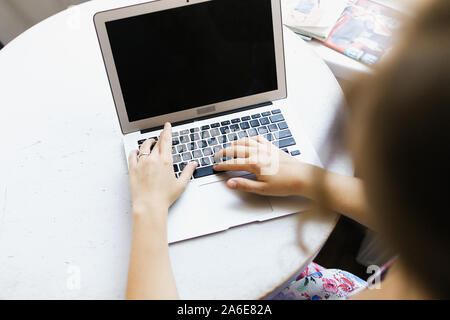 Blurry girl working with laptop, focus on computer. Stock Photo