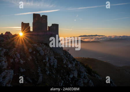 Ruins of medieval castle of Rocca Calascio at sunny morning, with foggy landscape in background and sunstar, Abruzzo, Italy