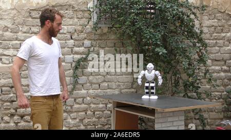 A humanoid robot teaches a young man to dance. The man sees the robot via head mounted display. The robot has a lot of patience and it repeats the same movements precisely. Stock Photo