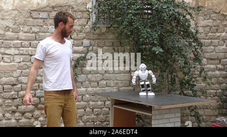 A humanoid robot teaches a young man to dance. The man sees the robot via head mounted display. The robot has a lot of patience and it repeats the same movements precisely. Stock Photo