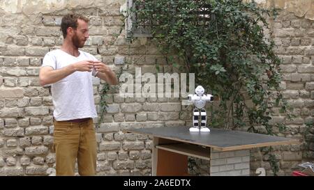 A humanoid robot teaches a young man to dance. The man sees the robot via head mounted display. The robot has a lot of patience and it repeats the same movements precisely. Stock Photo