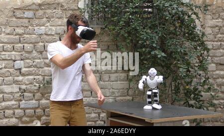 A humanoid robot teaches a young man to dance. The man sees the robot via head mounted display. The robot has a lot of patience and it repeats the same movements precisely. Stock Photo