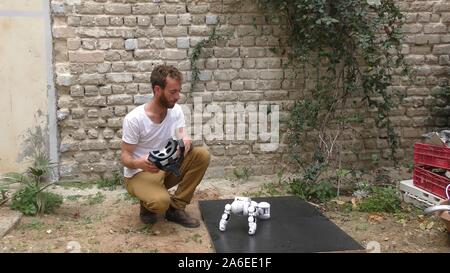 A humanoid robot teaches a young man to dance. The man sees the robot via head mounted display. The robot has a lot of patience and it repeats the same movements precisely. Stock Photo