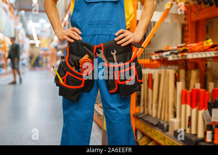 Male builder trying on tool belt in hardware store Stock Photo