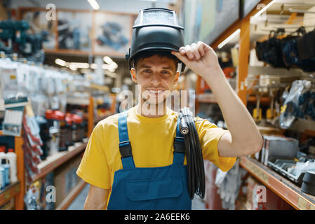 Builder choosing welding helmet in hardware store Stock Photo