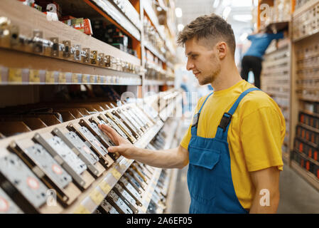 Male builder choosing door lock in hardware store Stock Photo