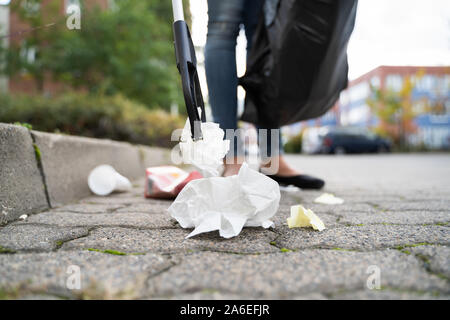 Woman Collecting Trash Outdoors Using Litter Picker Stock Photo