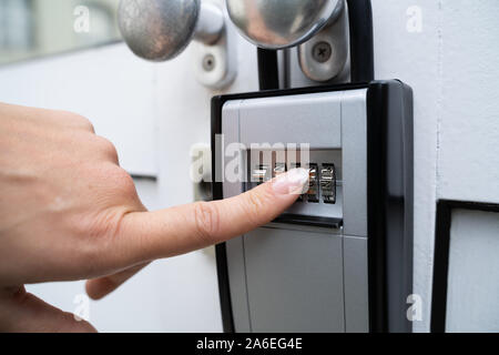 Woman Using Key Safe To Retrieve Keys From House Stock Photo