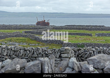 A ship wreck lying between stone walls on Inishere Island, Aran Islands, County Clare, Republic of Ireland. Stock Photo