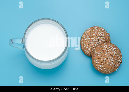 Cup of milk and oat cookies on blue background. Oat cookie with sesame seeds. Homemade baking. Stock Photo