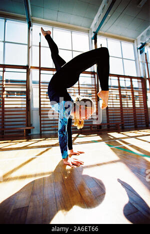Children. Teenage schoolgirl doing handstand in gymnasium. Stock Photo