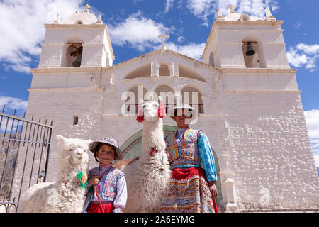 A portrait of a mother and her daughter with a llama and an alpaca in Maca, Peru. Stock Photo
