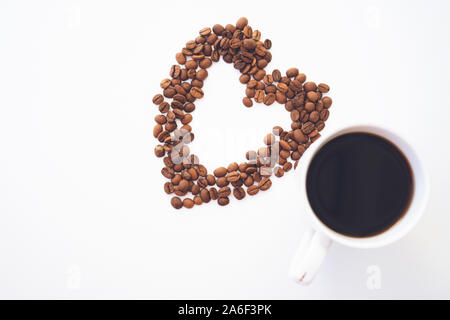 Heart shape made from coffee beans with cup of coffee on white background. I love coffee Stock Photo