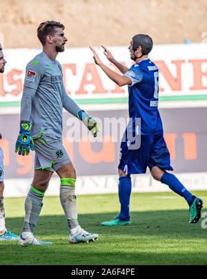 26 October 2019, Baden-Wuerttemberg, Karlsruhe: Soccer: 2nd Bundesliga, Karlsruher SC - Hannover 96, 11th matchday in the Wildparkstadion. The Hanoverian goalkeeper Ron-Robert Zieler (l) leaves the field after a yellow-red card. In the background, the Karlsruhe player cheers for Daniel Gordon's 3-3 goal. Photo: Uli Deck/dpa - IMPORTANT NOTE: In accordance with the requirements of the DFL Deutsche Fußball Liga or the DFB Deutscher Fußball-Bund, it is prohibited to use or have used photographs taken in the stadium and/or the match in the form of sequence images and/or video-like photo sequences. Stock Photo