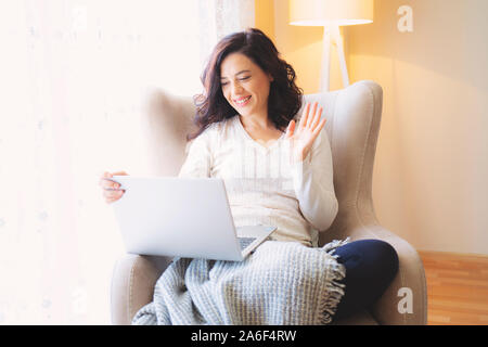 Smiling woman, freelancer having a video call, online web interview on a laptop in her home room, near window Stock Photo