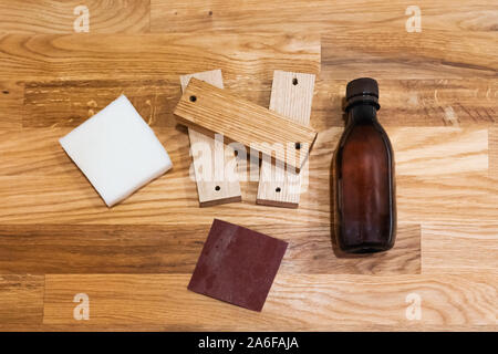 Wood furniture care kit on the Oak oiled wood plank table. Sandpaper, Oil, Sponge. Stock Photo