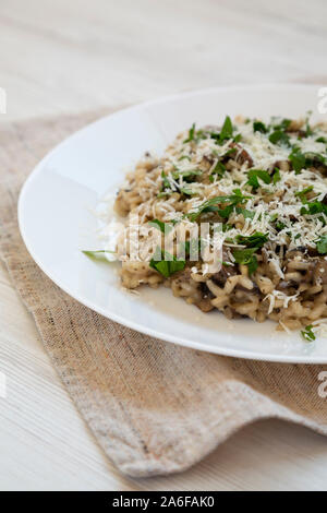 Homemade mushroom risotto on a white plate on a white wooden background, side view. Close-up. Stock Photo